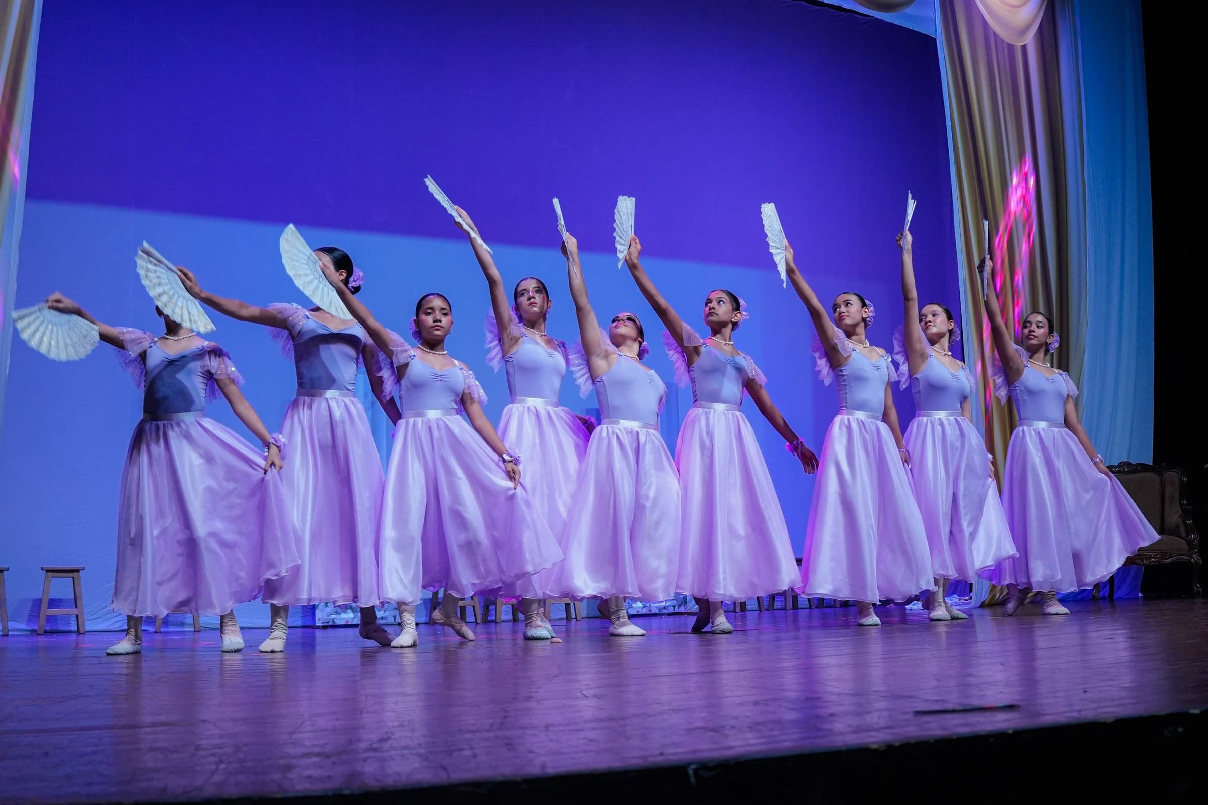 Bailarinas con vestidos lila bailando con abanicos