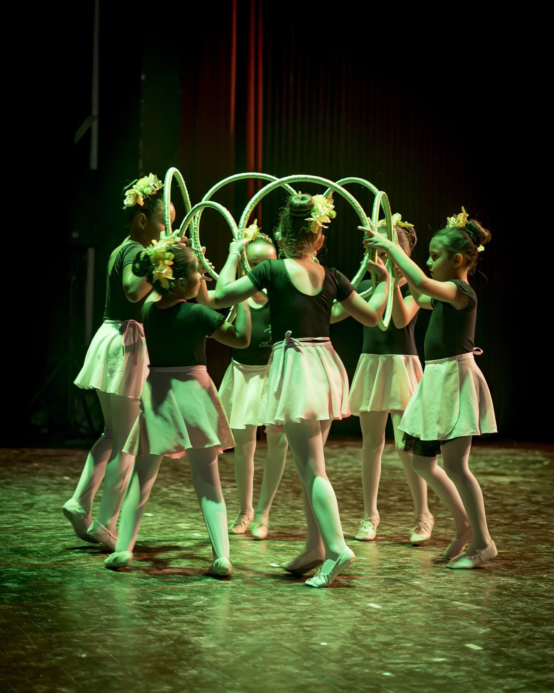 Bailarinas formando un arco con aros decorados con flores