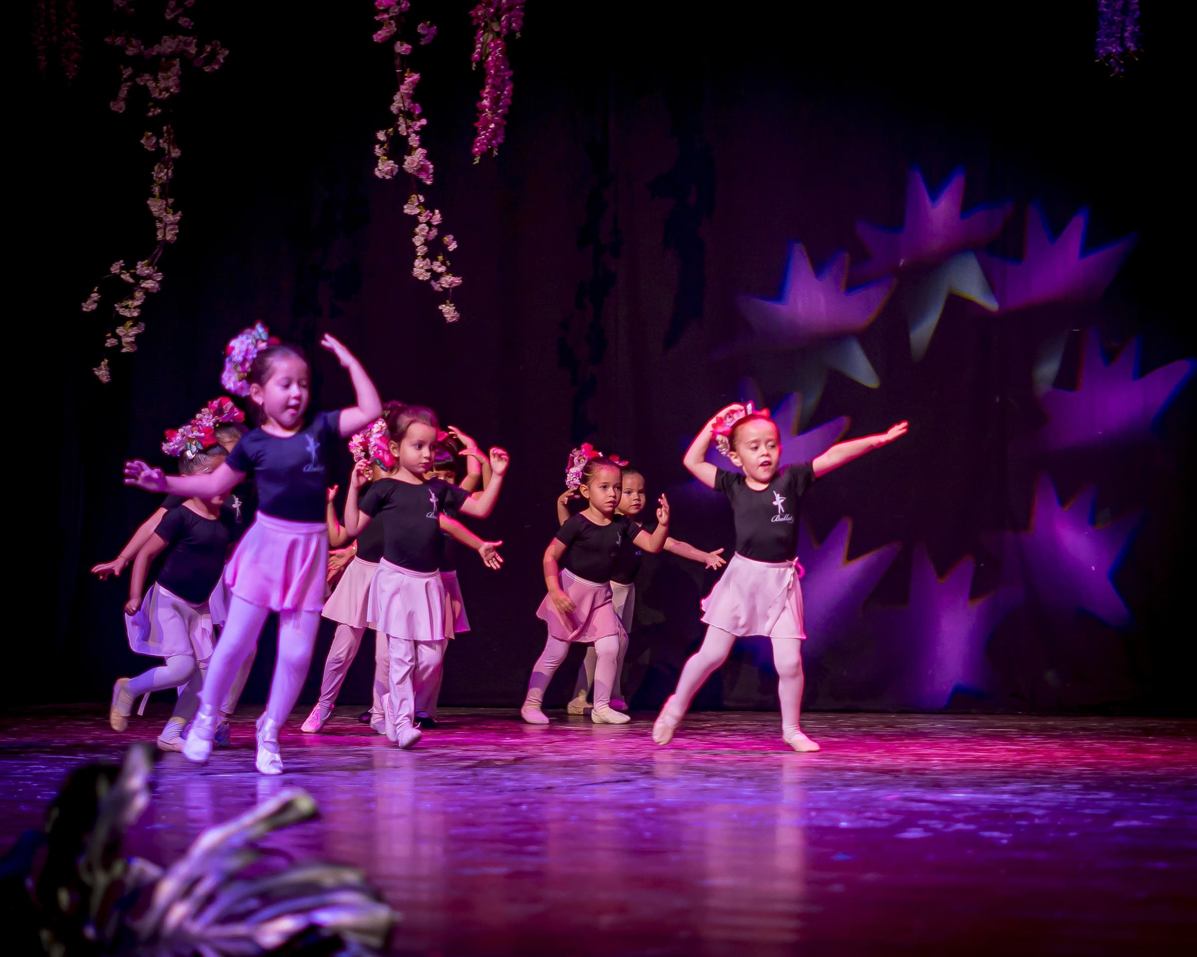 Niñas bailarinas con tutús rosados bajo luces moradas
