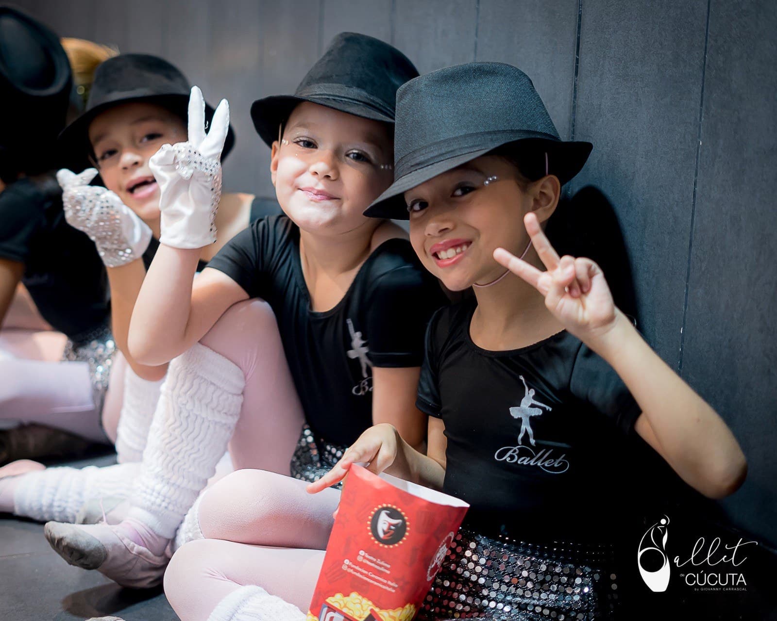 Niñas bailarinas con sombreros tipo fedora entre bambalinas