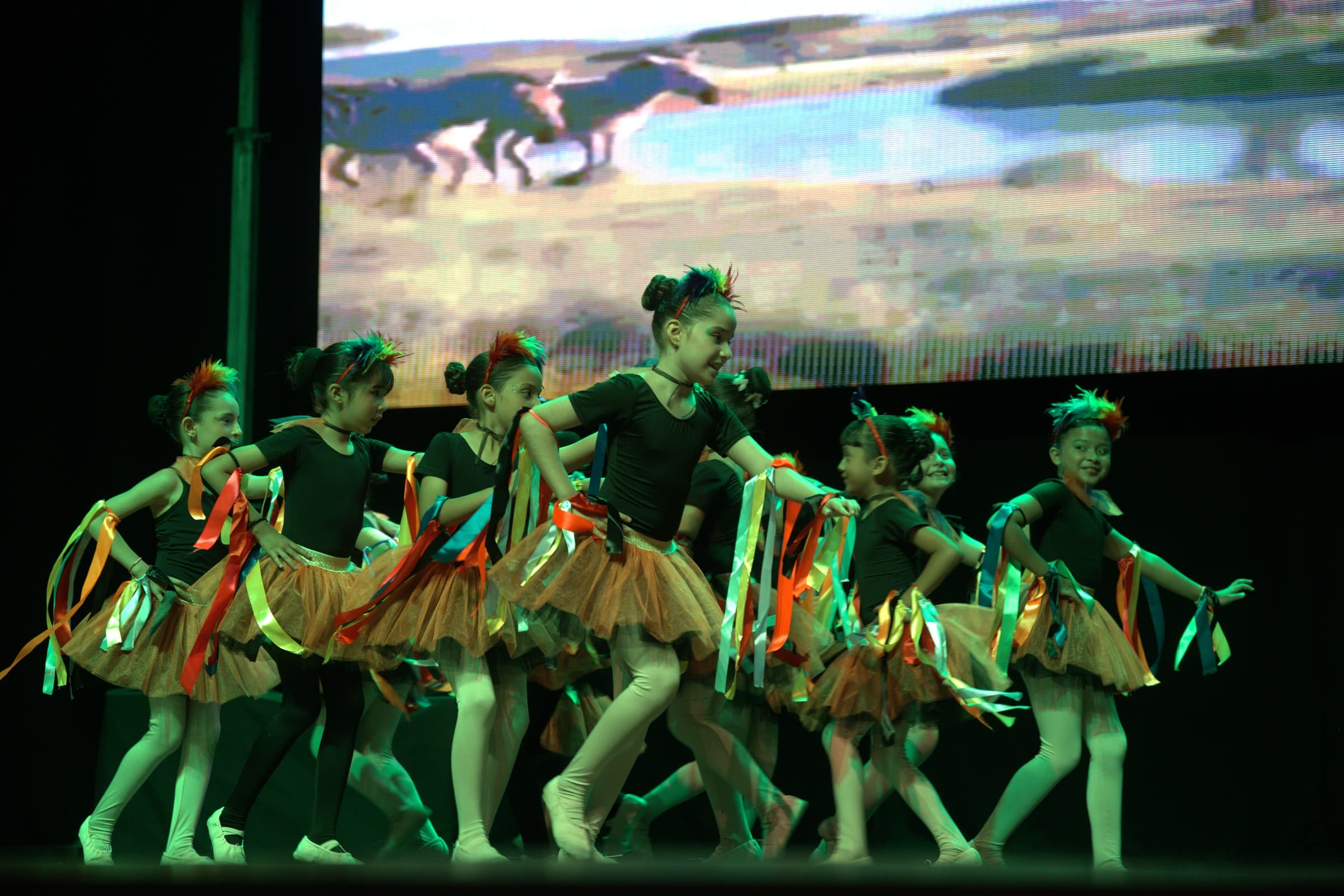 Grupo de niñas bailarinas con tutús y cintas de colores en escena