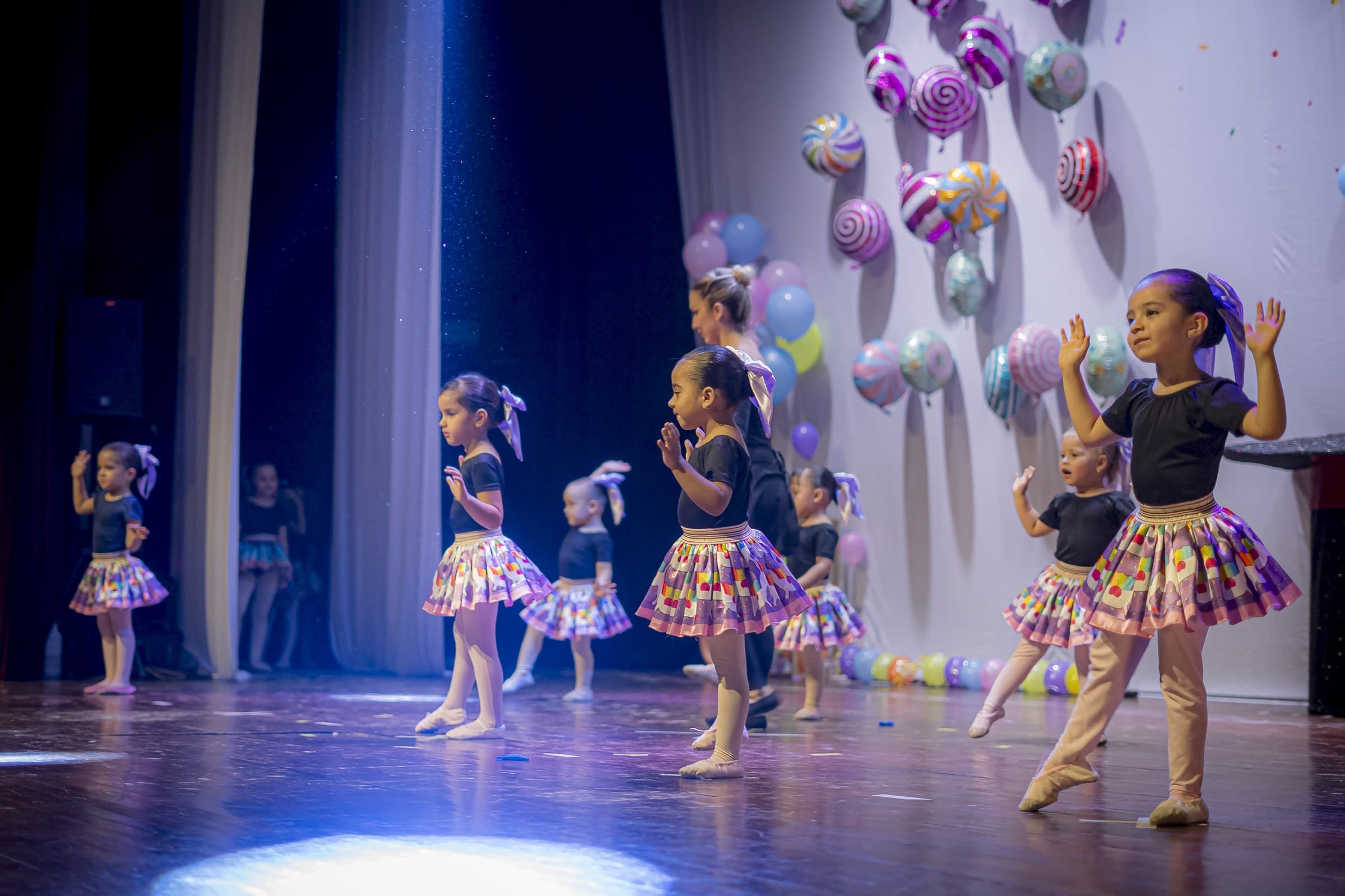 Niñas bailarinas con faldas de dulces frente a un decorado de globos y confites