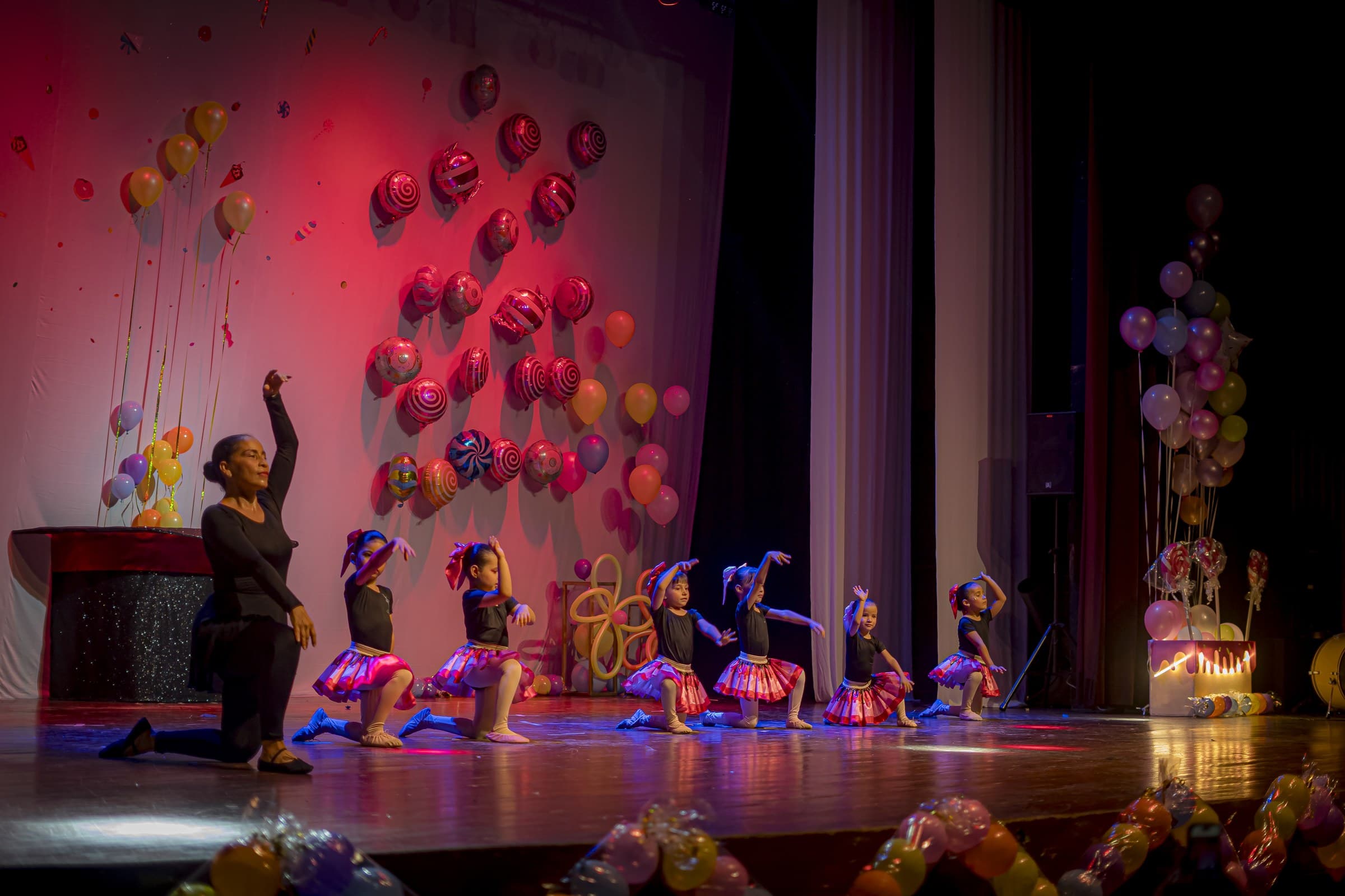 Bailarinas y su profesora en escena, con un decorado de dulces de fondo
